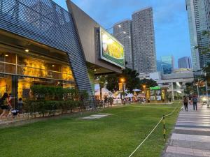 a building in a city with people walking on the grass at FameStaycation at FAME Residences in Manila