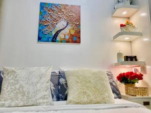 a bed with a pillow and a painting on the wall at FameStaycation at FAME Residences in Manila +12 photos