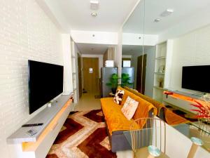 a living room with a couch and a large tv at FameStaycation at FAME Residences in Manila