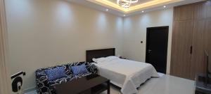 a white bedroom with a bed and a black door at Villa 6 in Ajman 