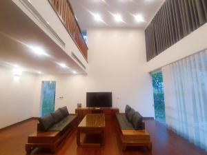 Una sala de estar con un sofá y un televisor. en Villas Vedana Cuc Phuong, en Thượng Sung