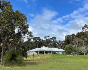 une femme debout devant une maison blanche dans l'établissement Heartbeat Retreat - Luxury Estate with Gym & Sauna, à Dunsborough