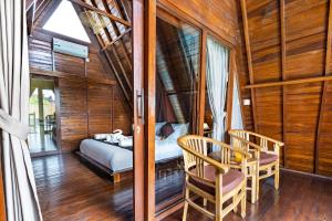 a bedroom with a bed and two chairs at Lumbung Sari villa ubud in Ubud