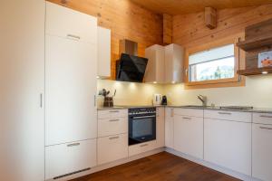 a kitchen with white cabinets and wooden walls at Pearl OG in Fiesch +8 photos