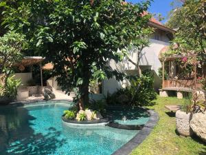 a swimming pool in a yard with a tree at Sampian Cottages Bingin in Uluwatu