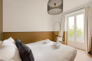 a bedroom with a white bed with a window at L'ATELIER 2 - Vintage KEYWEEK downtown Biarritz Centre in Biarritz