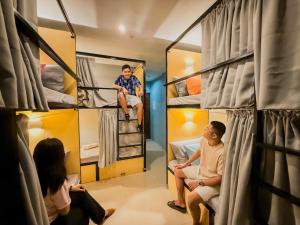 un gruppo di persone seduti in una stanza con letti a castello di Goofy Ants Hostel a Città di Puerto Princesa