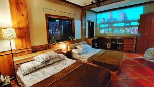 バギオにあるFamily Room 1A Transient Baguio Parking Wifiのベッド2台と大きなスクリーンのある部屋