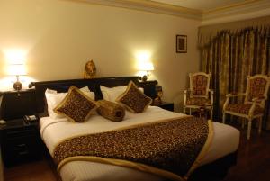 a bedroom with a large bed with four pillows at The Nagpur Ashok in Nagpur