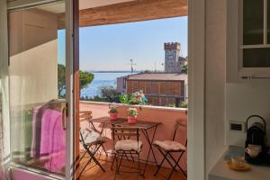 Garda Blue Lake Home Luxury Appartment في ديسينسانو ديل غاردا: شرفة مع طاولة وكراسي وإطلالة على المحيط