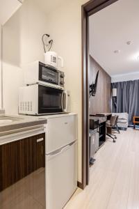 una cucina con forno a microonde e un soggiorno di アンドステイ竹ノ塚201 a Tokyo