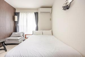 una camera da letto con un letto bianco e una sedia di アンドステイ竹ノ塚201 a Tokyo
