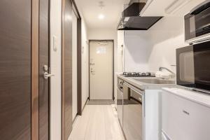 una piccola cucina con lavello e microonde di アンドステイ竹ノ塚201 a Tokyo