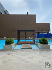 a building with a blue swimming pool with two plants at Perfect Staycation in Duma -Marina Spatial Condo in Dumaguete