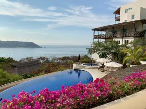 Una piscina al lado de un edificio con flores rosas. en The Best View in Brisas Marques, en Acapulco