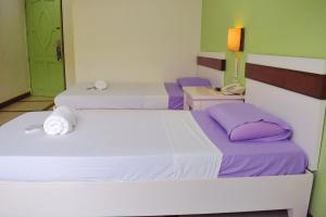 two beds in a room with purple and green walls at The Inns Bacolod in Bacolod +5 photos