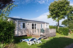 a tiny house with two chairs on a deck at Camping La Vallée in Houlgate