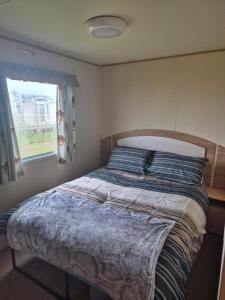 ein Bett in einem Schlafzimmer mit Fenster in der Unterkunft Woods caravan in Ingoldmells