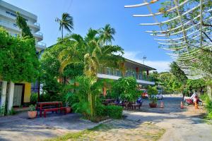 a building with palm trees and benches in front of it at Thai Hoa Mui Ne Resort in Mui Ne