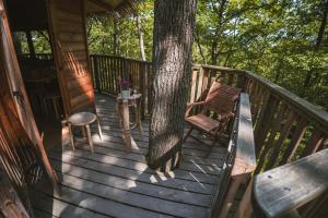 a porch of a cabin with a tree and a bench at TREE HOUSE U Mravence in Jinačovice