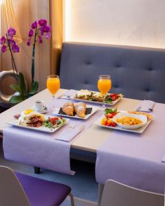 a table with two plates of food and two glasses of orange juice at The Purple Hotel - Adults Only in San Antonio