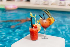 two cocktails on a table next to a swimming pool at The Purple Hotel - Adults Only in San Antonio
