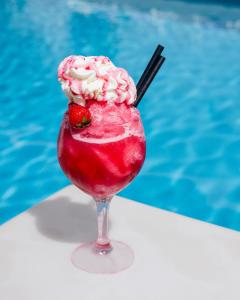 a drink with a strawberry in a glass next to a pool at The Purple Hotel - Adults Only in San Antonio