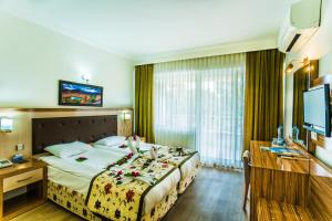 a hotel room with a bed and a desk and a television at Bieno Venüs Hotel - All Inclusive in Side +72 photos