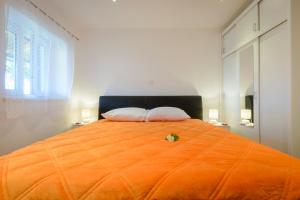 1 cama grande de color naranja con 2 almohadas encima en Apartments Dubrovnik Palm Tree Paradise, en Dubrovnik