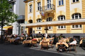 un grupo de personas sentadas en mesas frente a un edificio en Brauhaus Gummersbach GmbH en Gummersbach