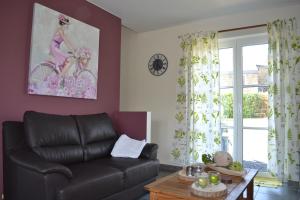 sala de estar con sofá de cuero y mesa en Gîte La Clef des Champs en Libin