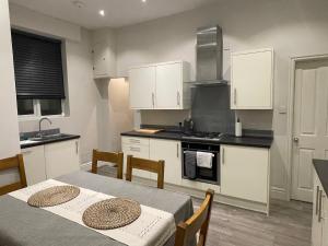 a kitchen with white cabinets and a table with chairs at Little Hebden Bridge House in Hebden Bridge