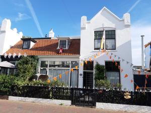 a white house with a fence in front of it at Little Beach House - Free parking in Zandvoort