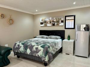 a bedroom with a bed and a refrigerator in it at Bachelor Flat B in Cape Town