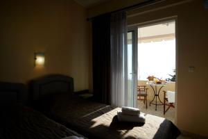 1 dormitorio con 1 cama y puerta que da a un patio en Evoikos beach & resort, en Livanates