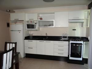 cocina con armarios blancos y encimera negra en Novo Lar 1 Bombinhas (Eliseos), en Bombinhas