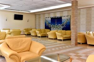 a waiting room with yellow chairs and a painting on the wall at Les Magnolias Hotel in Primorsko