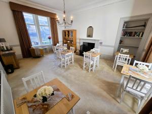 a living room with tables and chairs and a fireplace at Lochwood House & The Wild Spa in Lochgoilhead