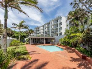 Un gran edificio de apartamentos con piscina y palmeras. en Chakas Cove, en Ballito