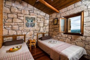 a bedroom with two beds and a stone wall at Panoramic View Villa in OliveGroves in Heraklio +8 photos