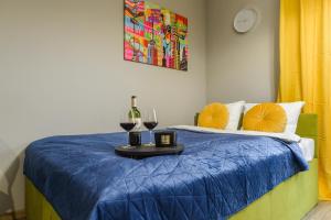 a bed with a blue comforter and two glasses of wine at Lumina I Comfy Apartments with Balcony I Parking I Pasaż Łódzki in Łódź