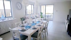 a dining room with a table with chairs and a clock at Eglinton Elegance - Hamptons Retreat in Yanchep