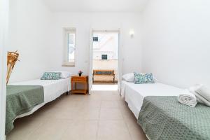 a white room with two beds and a table at Casa degli Oleandri in Ostuni