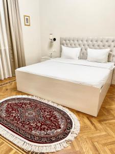 a bedroom with a large white bed and a rug at White Lilies Spacious 2-Bedroom Sea View in Baku