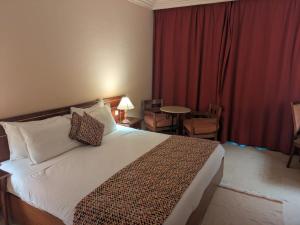 ein Hotelzimmer mit Bett, Tisch und Stühlen in der Unterkunft Hôtel LE CONSUL in Tunis + 17 Fotos