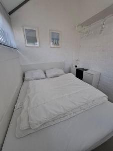 a white bed in a small room with two pillows at Rekerlanden 90 in Schoorldam +25 photos