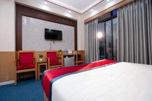 a hotel room with a bed and two chairs and a television at Hotel Safa Residency - DHAKA in Dhaka