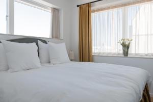a white bed with white pillows in a bedroom with windows at Clover House by Daniel&Jacob's in Copenhagen