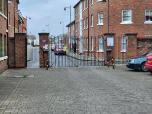 a gate in front of a brick building with cars at Westgate Apartment Canterbury 2bed 2bath Parking in Hackington