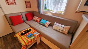 a small couch with pillows and books on it at Mobil-home 3 chambres climatisé sur le domaine 4 étoiles Rivages des Landes in Aureilhan +17 photos